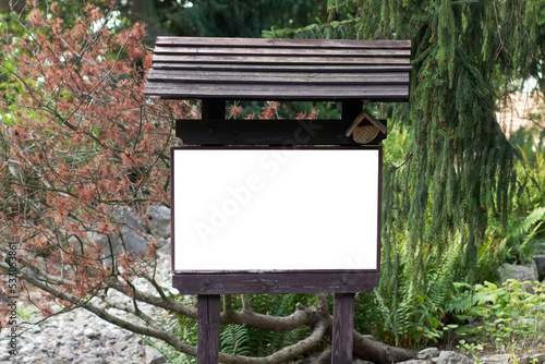 A white sheet of paper on a wooden information carrier with a mockup installed in a forest park © yarm_sasha