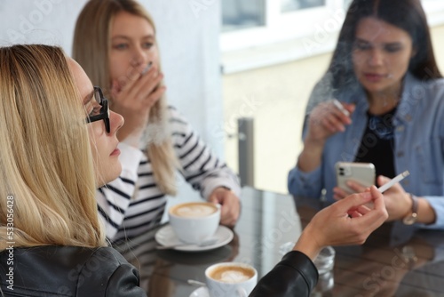 Women smoking cigarette at table in outdoor cafe