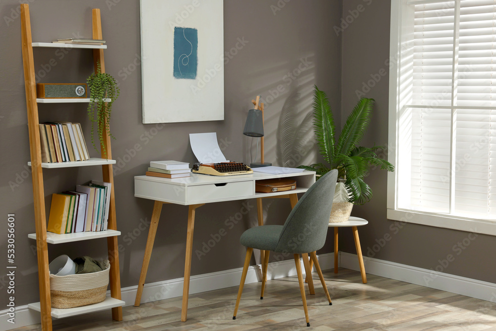 Fototapeta premium Comfortable writer's workplace interior with typewriter on desk near grey wall