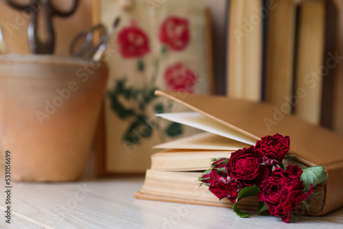 Beautiful dried flowers in book on wooden table