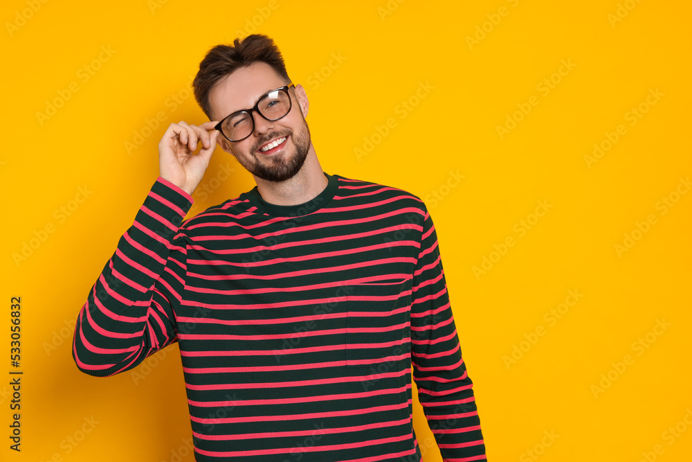 Handsome man in striped sweatshirt and eyeglasses on yellow background, space for text Handsome man in striped sweatshirt and eyeglasses on yellow background, space for text