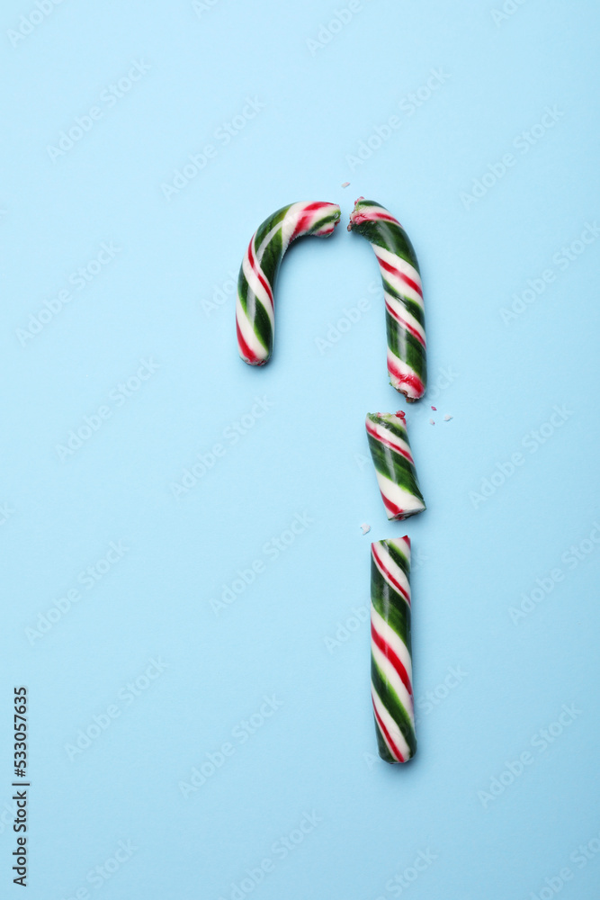 Broken sweet Christmas candy cane on light blue background, top view Broken sweet Christmas candy cane on light blue background, top view