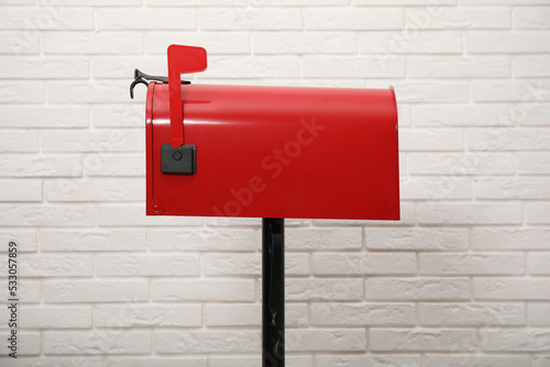 фотографія Closed red letter box near white brick wall