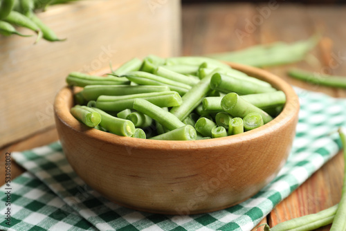 Fresh green beans in bowl on wooden table, closeup