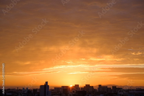 都会の夜明け。神戸市街地からの日の出。オレンジ色に染まる空と雲。神戸市街地から芦屋大阪方面を臨む