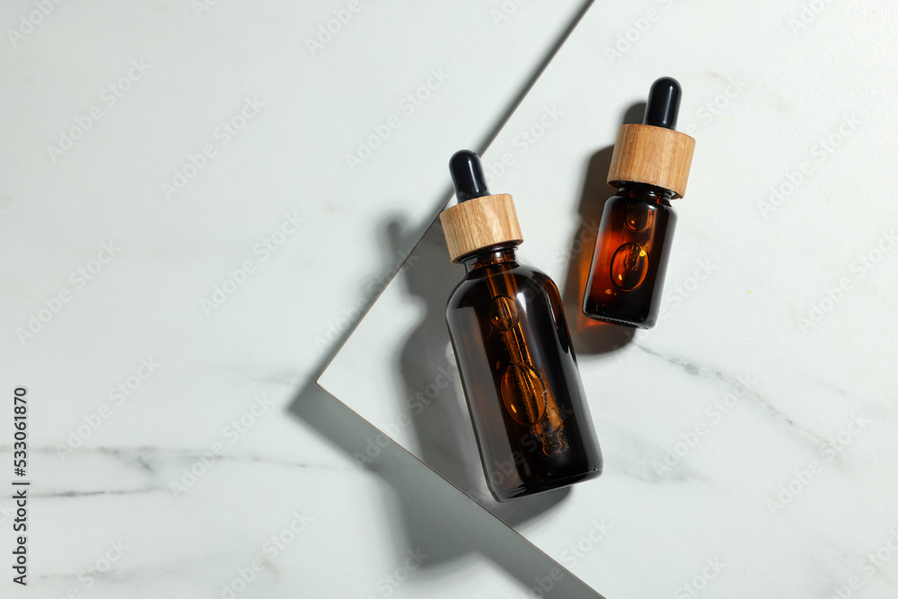 Glass bottles of essential oil on white marble table, flat lay Glass bottles of essential oil on white marble table, flat lay