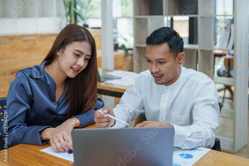 startup business, portrait of two entrepreneurs using computers and financial budget documents to make marketing plans to increase profits