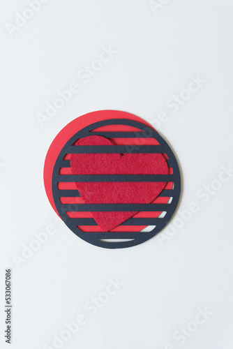 red fabric heart interlaced in a round gridiron on blank paper