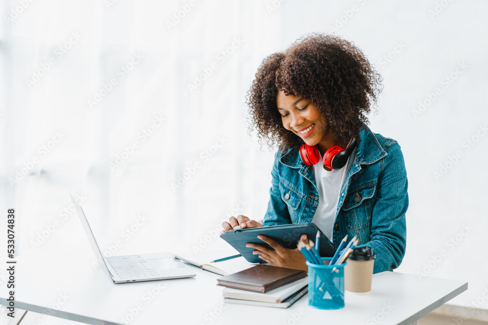 Young pretty african amerian woman studying online with laptop at living room. Young pretty african amerian woman studying online with laptop at living room.