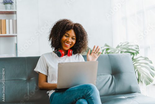 Young pretty african amerian woman studying online with laptop at living room.