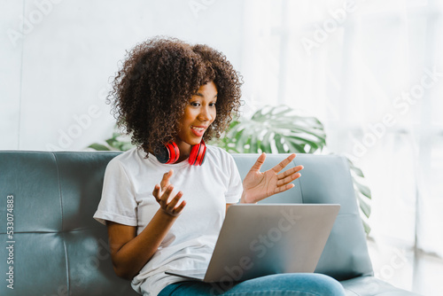 Young pretty african amerian woman studying online with laptop at living room. photo