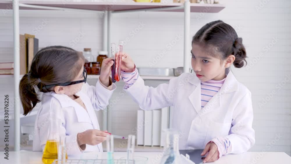 4K, Two cute schoolgirls are naughty in the school lab mixing colors in test tubes while waiting for the teacher to teach with fun. Concept education, Science experiments, Chemistry, Children 4K, Two cute schoolgirls are naughty in the school lab mixing colors in test tubes while waiting for the teacher to teach with fun. Concept education, Science experiments, Chemistry, Children