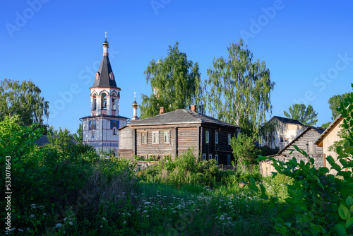Wooden houses on a blooming meadow and the bell tower of Znamenskaya Church built in 1788 in the city of Pereslavl-Zalessky, Russia