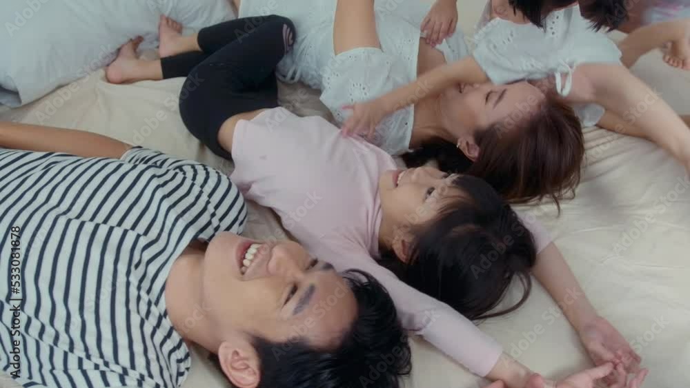 Asian Parents with two little daughters playing, jumping on the bed in bedroom, happy family concept Asian Parents with two little daughters playing, jumping on the bed in bedroom, happy family concept