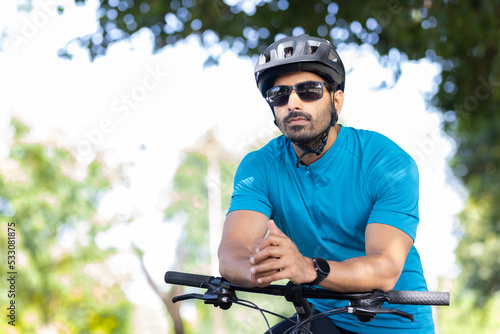 Thoughtful young man leaning on bicycle.  © G-images