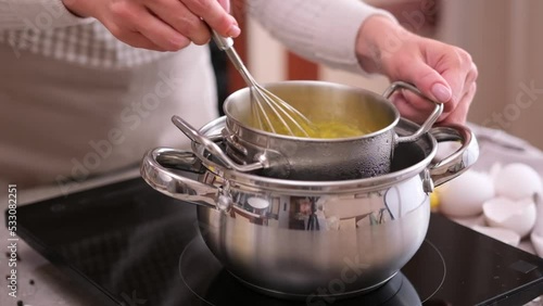 Cooking hollandaise sauce - Woman mixing egg yolks in metal steamer pot by a whisk