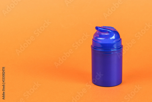 A blue bottle of aftershave gel on an orange background.