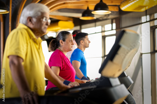 Men and woman in sportswear doing cardio workout at gym 