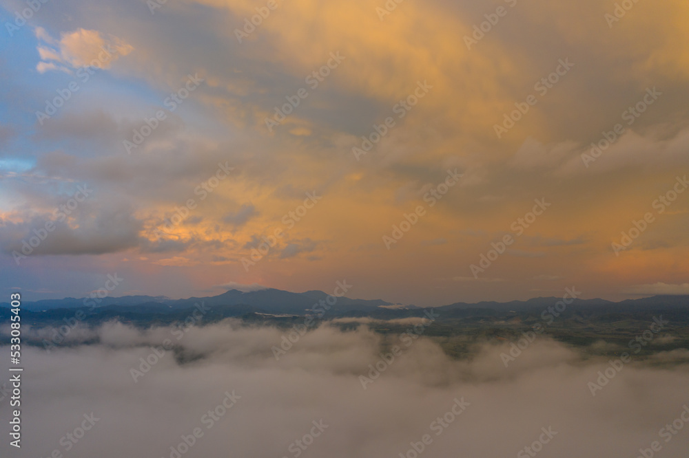 aerial view multicolored sky above the sea of mist..A sea of mist envelops the mountain peaks against the brightly colored sky at sunset..A sea of mist covers the mountain 
