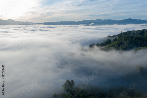 aerial view scenery sunrise above the mountain in tropical rainforest..slow floating fog blowing cover on the mountain look like as a sea of mist. .beautiful sunrise in the mist background.