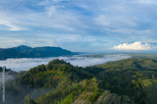 aerial view scenery sunrise above the mountain in tropical rainforest..slow floating fog blowing cover on the mountain look like as a sea of mist. .beautiful sunrise in the mist background. © Narong Niemhom