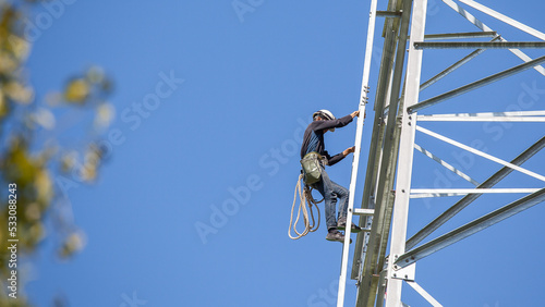 Worker climbing on transmission line steel tower