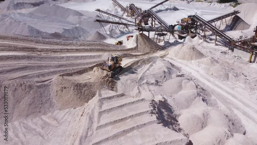 Aerial view of a mining crawler bulldozer in work in limestone quarry.