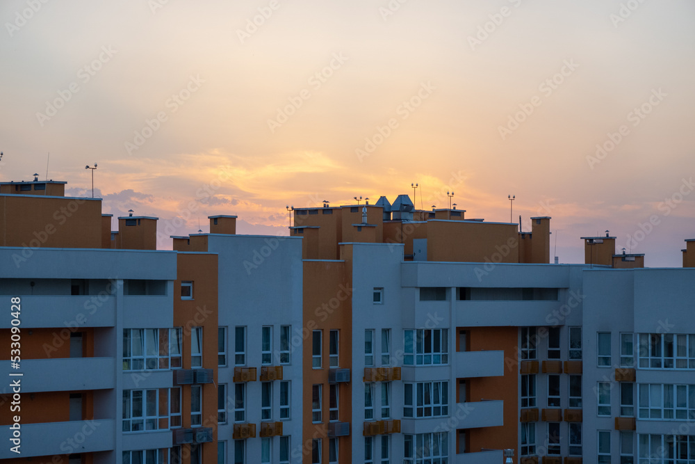 beautiful orange sunset over the city, visible city line of buildings and houses, darkness and sunbeam in sky, early morning, sunrise 