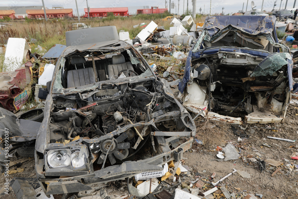 Details with destroyed cars or car parts in a makeshift scrap yard.