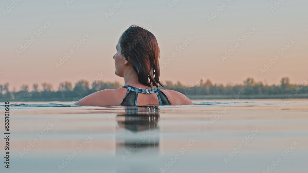 Young Caucasian Woman Standing Neck Deep in Calm Lake Water at Evening Sunset