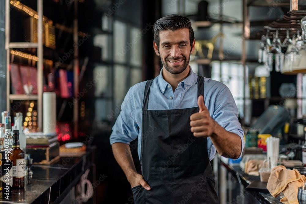 Photo of a handsome bartender doing thumb up pose behind the bar in a sky lounge bar in Bangkok Photo of a handsome bartender doing thumb up pose behind the bar in a sky lounge bar in Bangkok