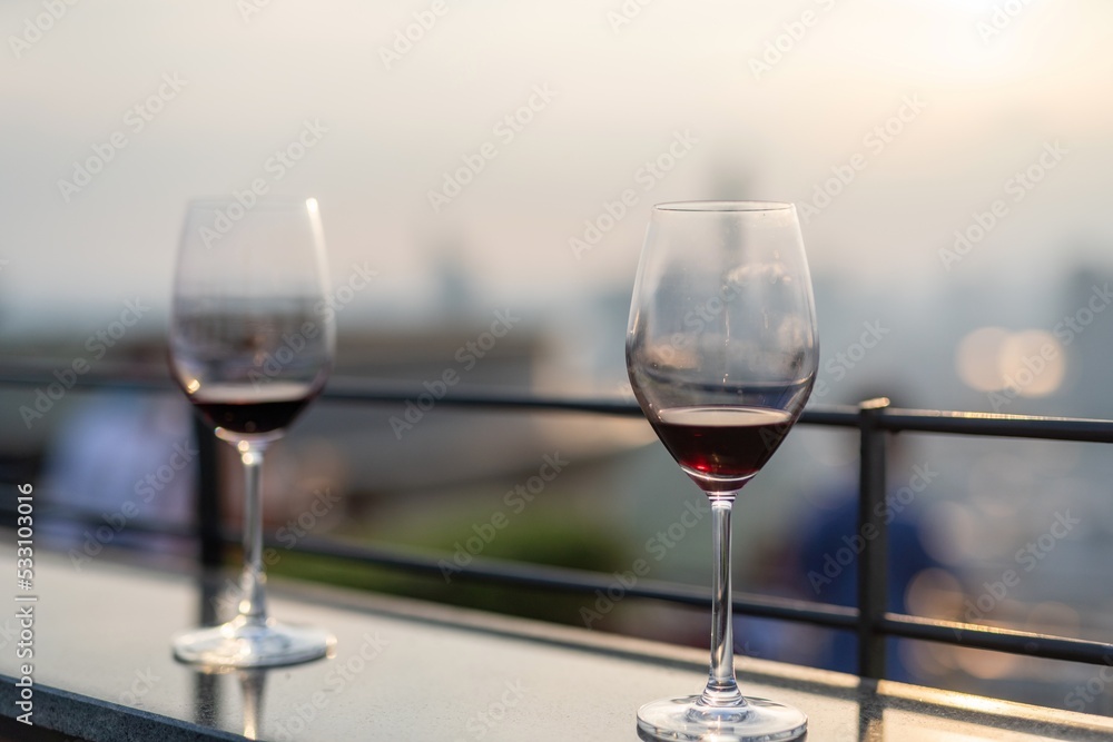 Photo of a pair of wineglasses with the background of sunset and Bangkok skyline