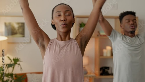 A healthy black couple doing yoga, meditation mindfulness exercises and stretching before working out from home. Good health, peace of mind and being active from the comfort of your house living room