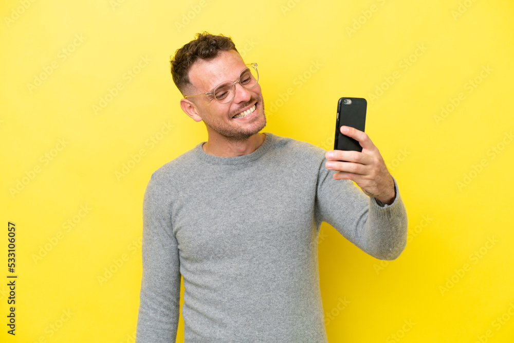 Young caucasian handsome man isolated on yellow background making a selfie Young caucasian handsome man isolated on yellow background making a selfie
