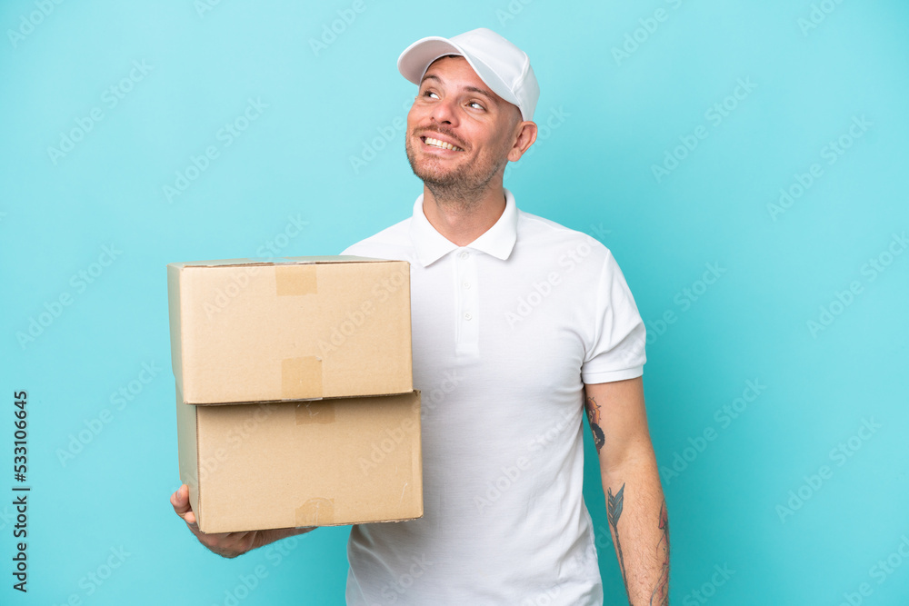 Delivery caucasian man isolated on blue background thinking an idea while looking up Delivery caucasian man isolated on blue background thinking an idea while looking up