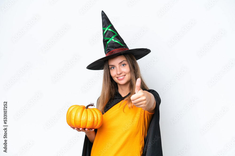 Young caucasian woman costume as witch holding a pumpkin isolated on white background with thumbs up because something good has happened Young caucasian woman costume as witch holding a pumpkin isolated on white background with thumbs up because something good has happened