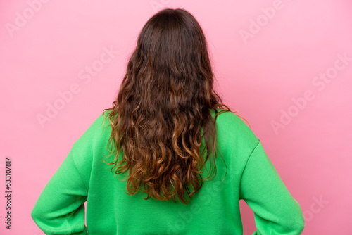 Young caucasian woman isolated on pink background in back position