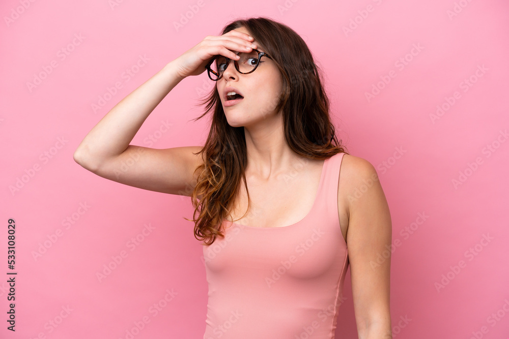 Young caucasian woman isolated on pink background doing surprise gesture while looking to the side Young caucasian woman isolated on pink background doing surprise gesture while looking to the side