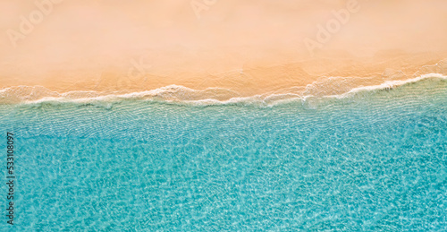 Summer seascape beautiful waves, blue sea water in sunny day. Top drone view. Sea aerial view, amazing tropical nature background. Beautiful bright sea waves surf on bright Mediterranean beach sand