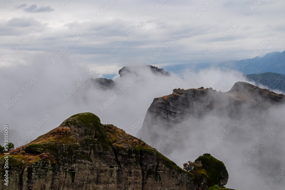 Scenic view of unique rock formations near Holy Monastery of Varlaam on cloudy moody day in Kalambaka, Meteora, Thessaly, Greece, Europe. Rocks overgrown with moss, misty fog coming up from valley