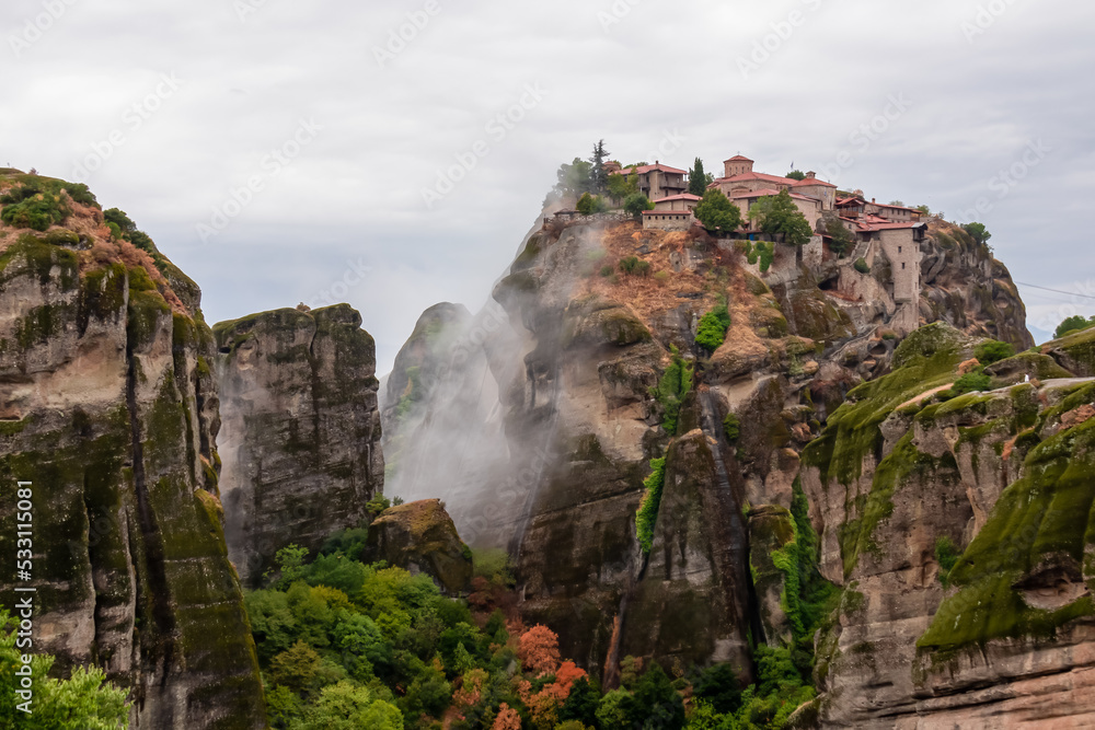 Scenic view of Holy Monastery of Great Meteoron appearing from fog, Kalambaka, Meteora, Thessaly, Greece, Europe. Mystical atmosphere in dramatic landscape. Landmark build on unique rock formations