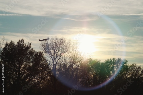 Silueta de un avión sobre la silueta de los árboles al atardecer. Silueta  de un avión de pasajeros despegando desde el aeropuerto Adolfo Suarez Madrid Barajas en España con los últimos rayos de sol. photo