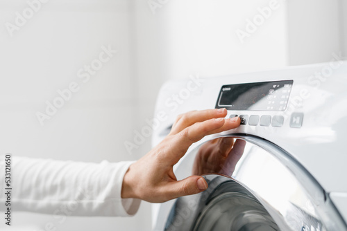 Картината върху платно female hand press button on washing machine indoors