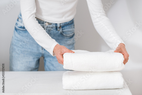 woman neatly folding terry towels on table indoors