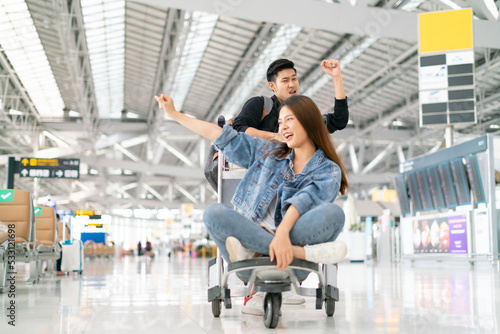 Young asian couple are happily waiting on a luggage trolley while waiting for a flight at airport terminal,opening international travel flights after the coronavirus 2019 (COVID-19) outbreak ends.