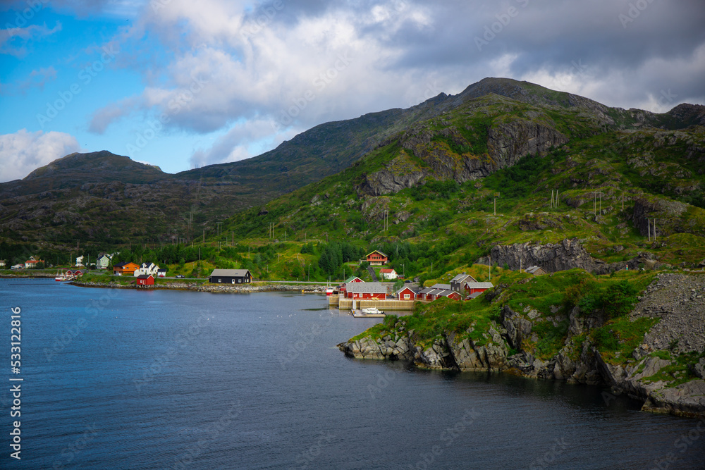 Typical red Norwegian fishermen's cottages and mountain ranges in the background. The photo was taken in the Lofoten Islands