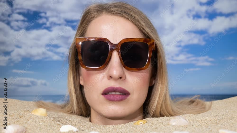 Woman buried in sand on beach with sunglasses Woman buried in sand on beach with sunglasses