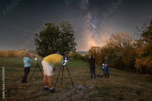 People photographing the milky way in nature. People with milky way, in the mountains. Light painting in a nightscape © Camille