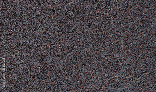 Soft rubber granular flooring surface close up dark red colored