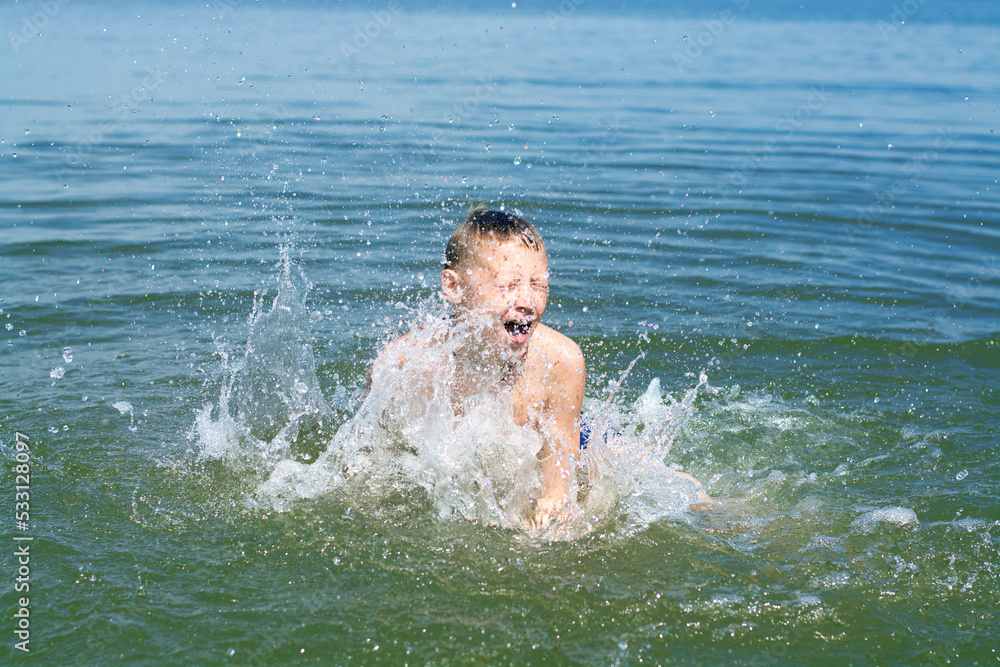 A boy plays in the water, splashes in the river A boy plays in the water, splashes in the river
